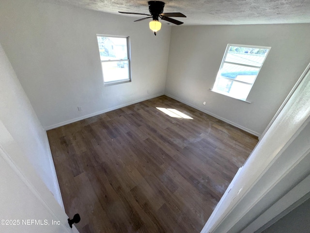 empty room with ceiling fan, dark wood-type flooring, and a textured ceiling