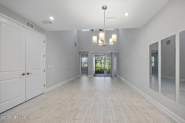 empty room with light hardwood / wood-style flooring and a chandelier