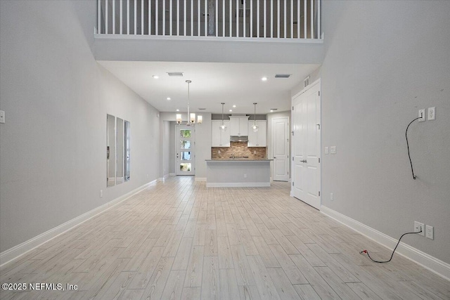 unfurnished living room with a high ceiling and light hardwood / wood-style floors