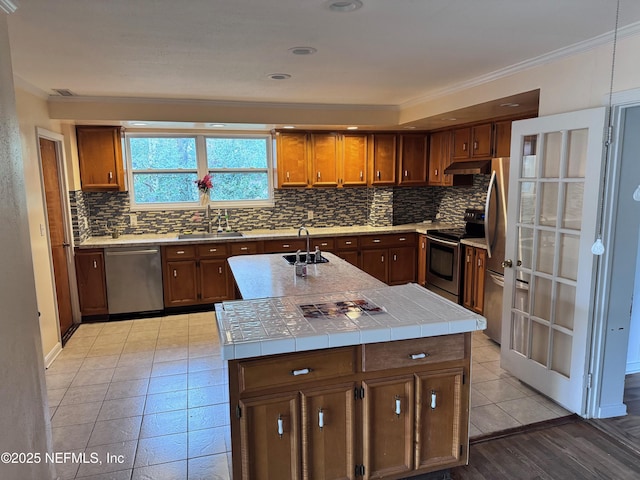 kitchen with sink, appliances with stainless steel finishes, tile counters, and an island with sink