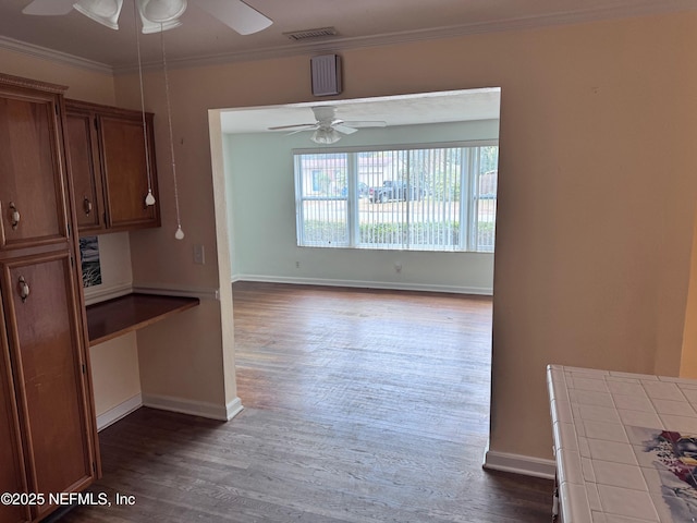 unfurnished dining area with ceiling fan, dark hardwood / wood-style flooring, and crown molding