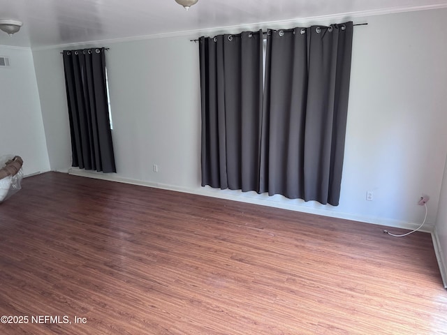 empty room with wood-type flooring and ornamental molding