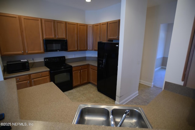 kitchen with sink, kitchen peninsula, and black appliances