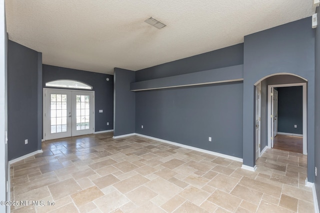 empty room with french doors and a textured ceiling