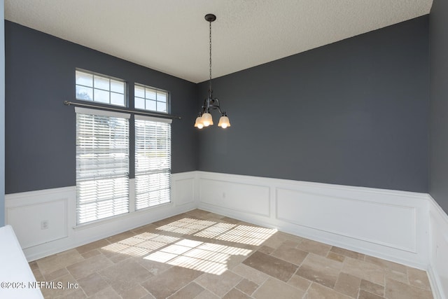 empty room with a chandelier and a textured ceiling