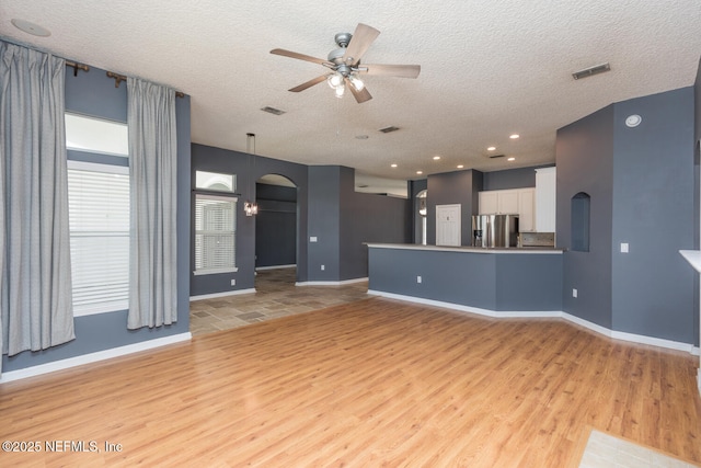 unfurnished living room featuring ceiling fan, light hardwood / wood-style floors, and a textured ceiling