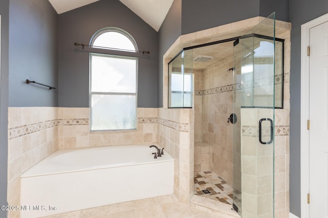 bathroom featuring lofted ceiling, plus walk in shower, and a wealth of natural light