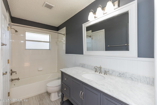 full bathroom with vanity, toilet, tiled shower / bath combo, and a textured ceiling