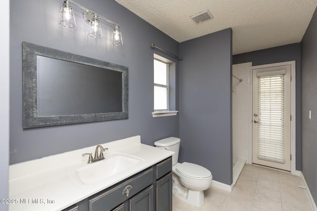 bathroom with vanity, tile patterned floors, toilet, and tiled shower