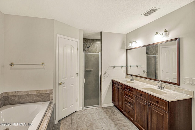 bathroom with tile patterned floors, vanity, plus walk in shower, and a textured ceiling