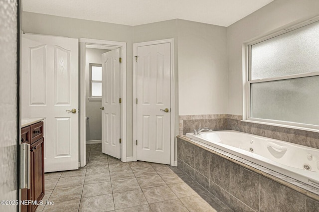 bathroom with tile patterned flooring, tiled tub, and vanity