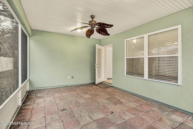 unfurnished sunroom featuring ceiling fan