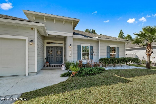 doorway to property with a garage and a yard