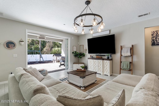 living room with a chandelier, a textured ceiling, and light tile patterned flooring