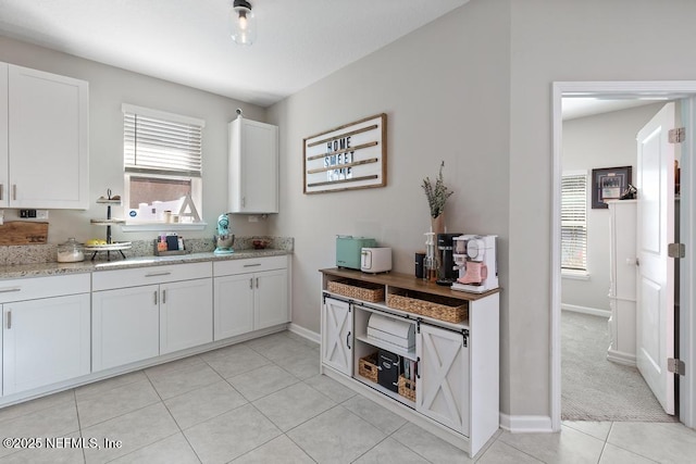 kitchen with light colored carpet, plenty of natural light, and white cabinetry