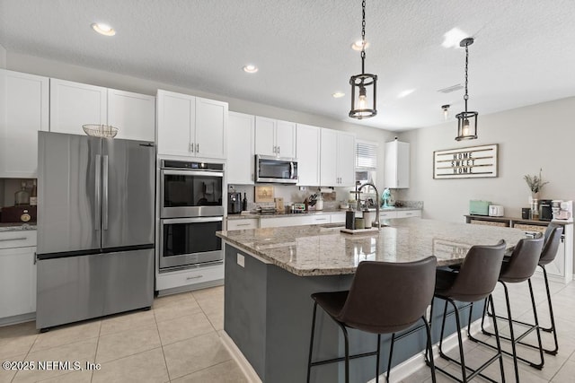 kitchen featuring sink, a kitchen island with sink, decorative light fixtures, and appliances with stainless steel finishes