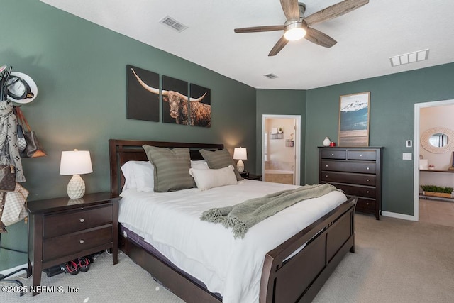 bedroom featuring ceiling fan, light colored carpet, and ensuite bathroom