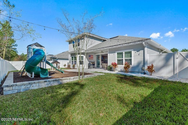 back of property with a lawn and a playground