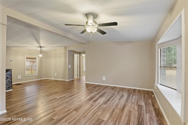 unfurnished room with hardwood / wood-style flooring, vaulted ceiling with beams, and ceiling fan