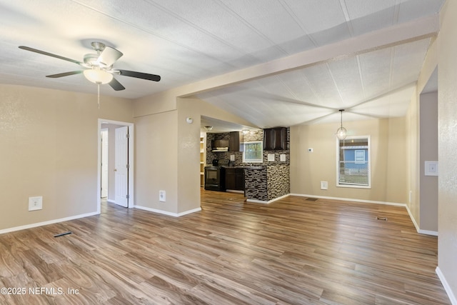 unfurnished living room featuring light wood-type flooring, vaulted ceiling, and plenty of natural light