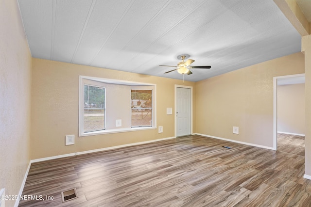 spare room with ceiling fan, a textured ceiling, and wood-type flooring