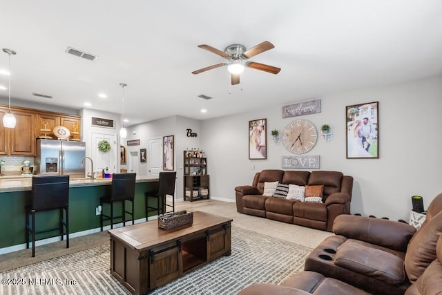 living room featuring sink, light colored carpet, and ceiling fan