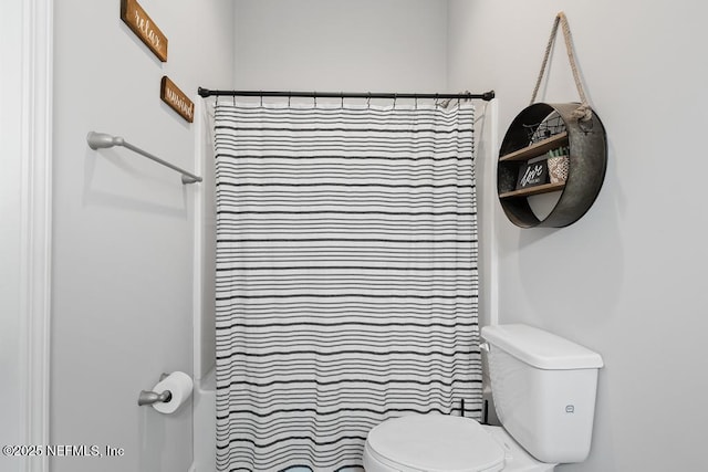 bathroom featuring a shower with curtain and toilet