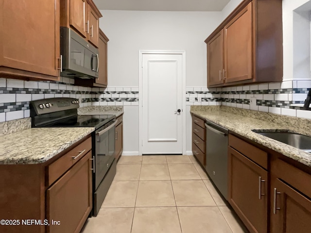 kitchen with light stone countertops, backsplash, light tile patterned floors, and stainless steel appliances