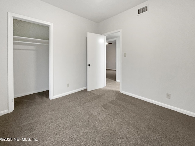 unfurnished bedroom featuring a closet and dark carpet