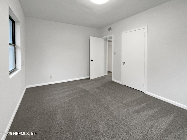 unfurnished room featuring dark colored carpet