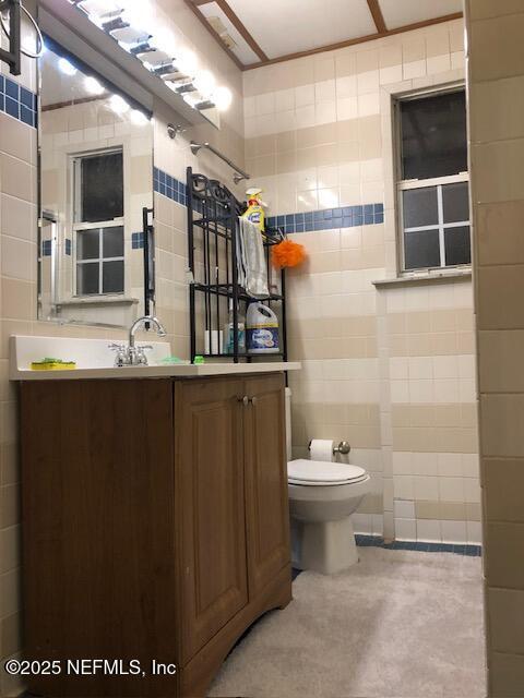 bathroom featuring vanity, toilet, and tile walls