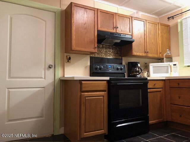 kitchen featuring electric range, dark tile patterned floors, and decorative backsplash