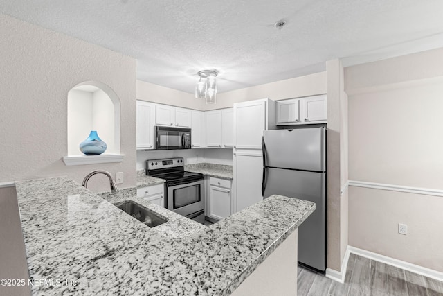 kitchen with stainless steel appliances, white cabinetry, sink, and kitchen peninsula