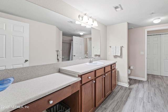 bathroom featuring vanity, a textured ceiling, and toilet