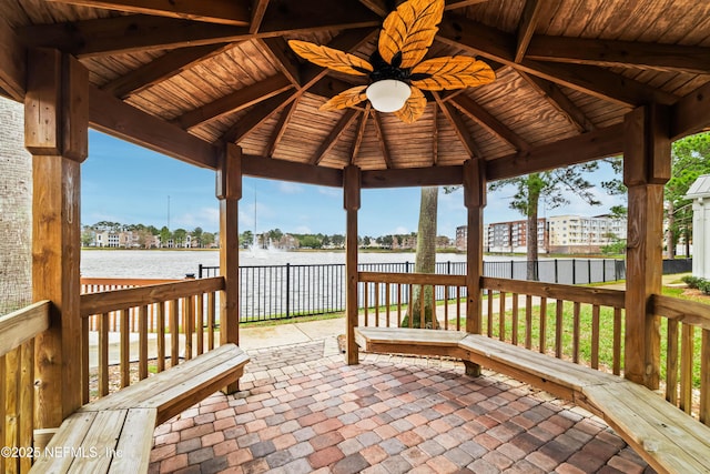 wooden terrace with a gazebo, ceiling fan, and a water view