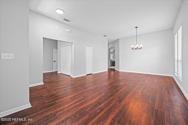 1560 Timber Trace Dr, Saint Augustine, FL 32092 - unfurnished living room featuring a chandelier, dark wood finished floors, arched walkways, and a textured ceiling