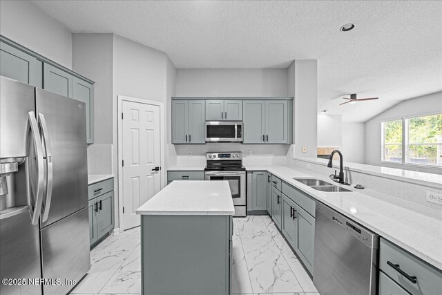 1560 Timber Trace Dr, Saint Augustine, FL 32092 - kitchen with appliances with stainless steel finishes, gray cabinetry, a textured ceiling, light marble finish flooring, and a center island
