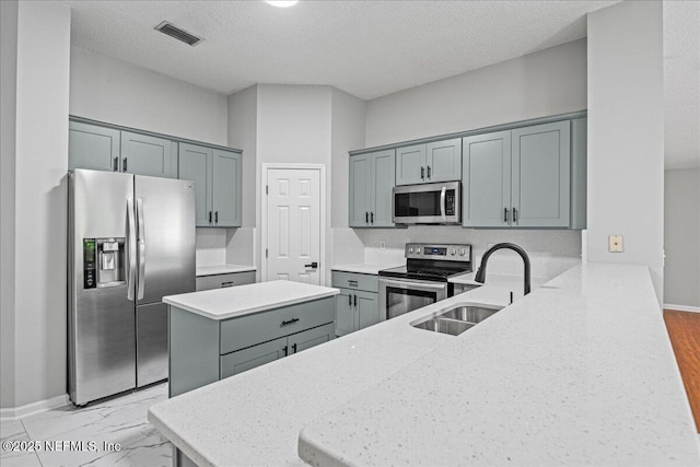 1560 Timber Trace Dr, Saint Augustine, FL 32092 - kitchen featuring appliances with stainless steel finishes, a peninsula, a kitchen island, a textured ceiling, and gray cabinetry