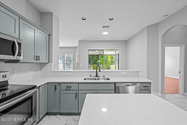 1560 Timber Trace Dr, Saint Augustine, FL 32092 - kitchen featuring stainless steel appliances, light marble finish flooring, gray cabinetry, arched walkways, and a textured ceiling