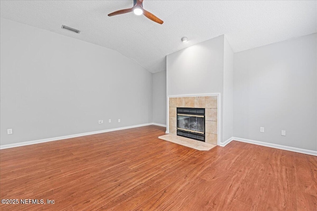 1560 Timber Trace Dr, Saint Augustine, FL 32092 - unfurnished living room featuring a textured ceiling, a tile fireplace, wood finished floors, vaulted ceiling, and ceiling fan