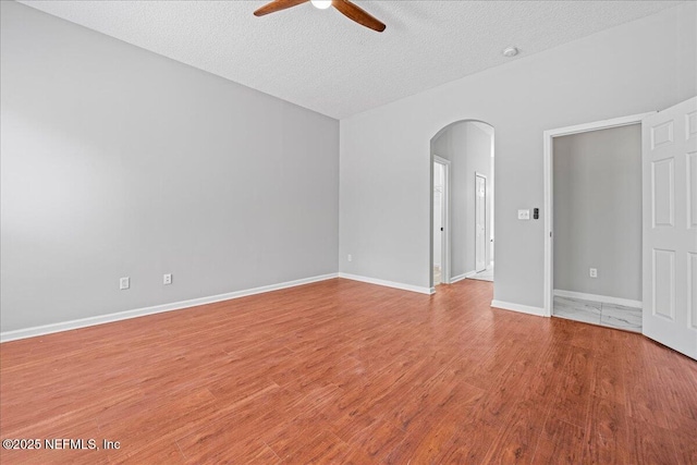 1560 Timber Trace Dr, Saint Augustine, FL 32092 - empty room featuring arched walkways, ceiling fan, wood finished floors, and a textured ceiling