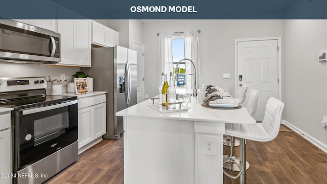 kitchen with a kitchen island with sink, a breakfast bar, white cabinetry, and appliances with stainless steel finishes