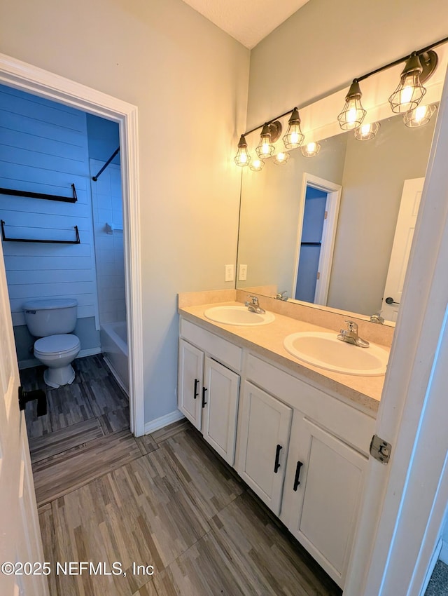 full bathroom featuring hardwood / wood-style flooring, vanity, washtub / shower combination, and toilet