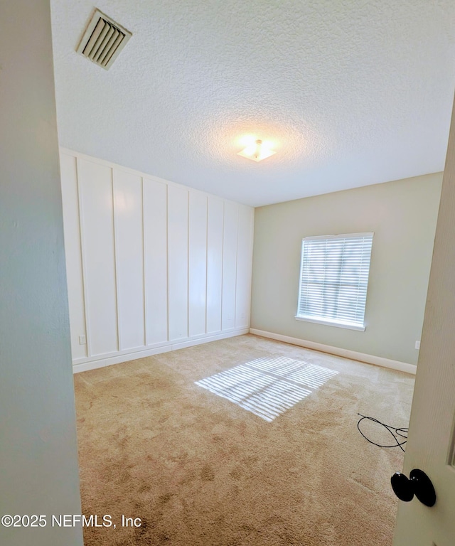 carpeted empty room with a textured ceiling