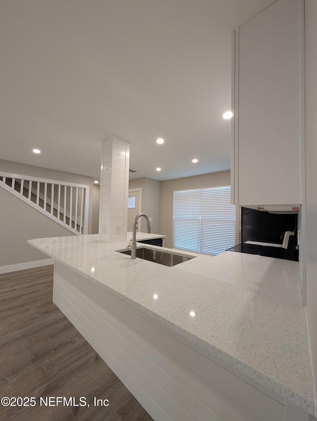 kitchen with sink, light stone countertops, and dark hardwood / wood-style floors