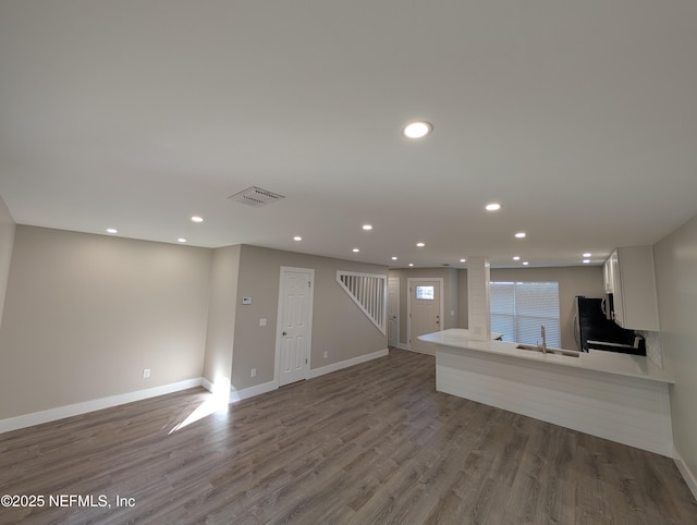 unfurnished living room featuring wood-type flooring and sink