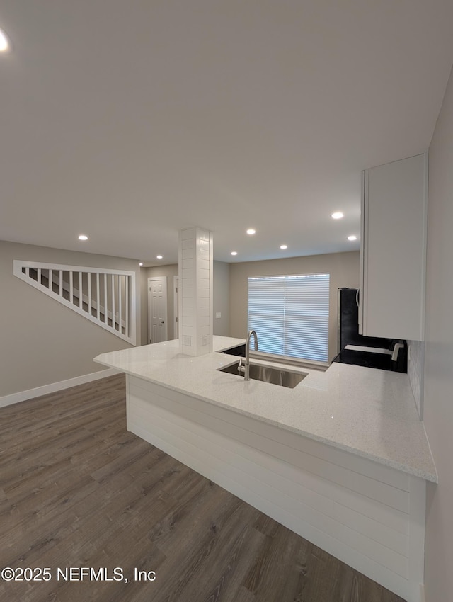 kitchen featuring dark hardwood / wood-style flooring, sink, and light stone counters