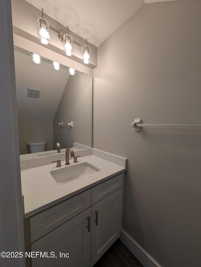 bathroom with vanity, vaulted ceiling, and toilet