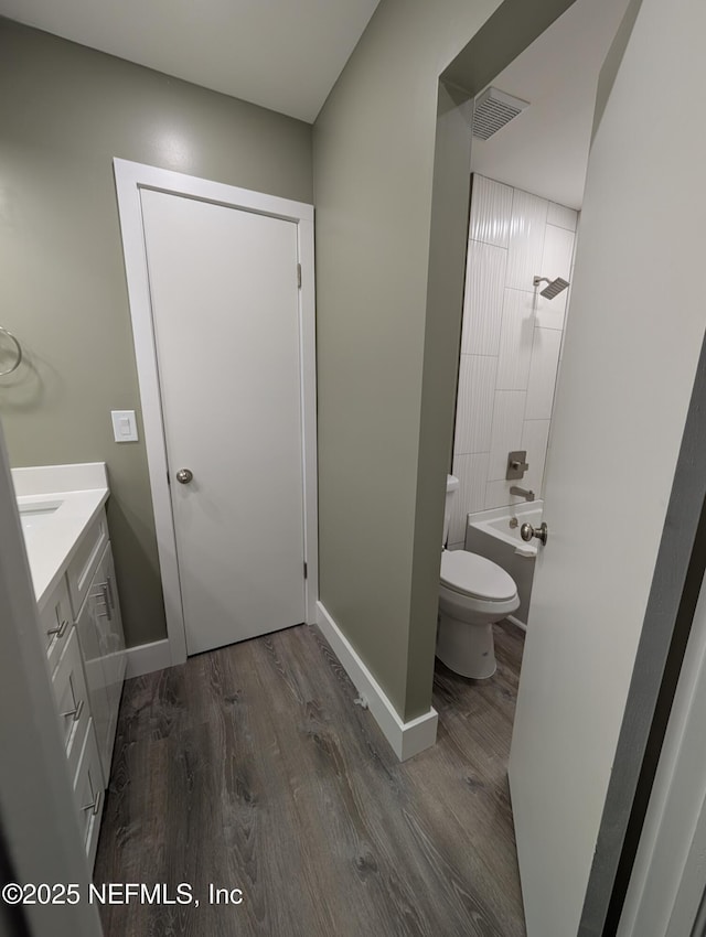 full bathroom with bathing tub / shower combination, wood-type flooring, vanity, and toilet