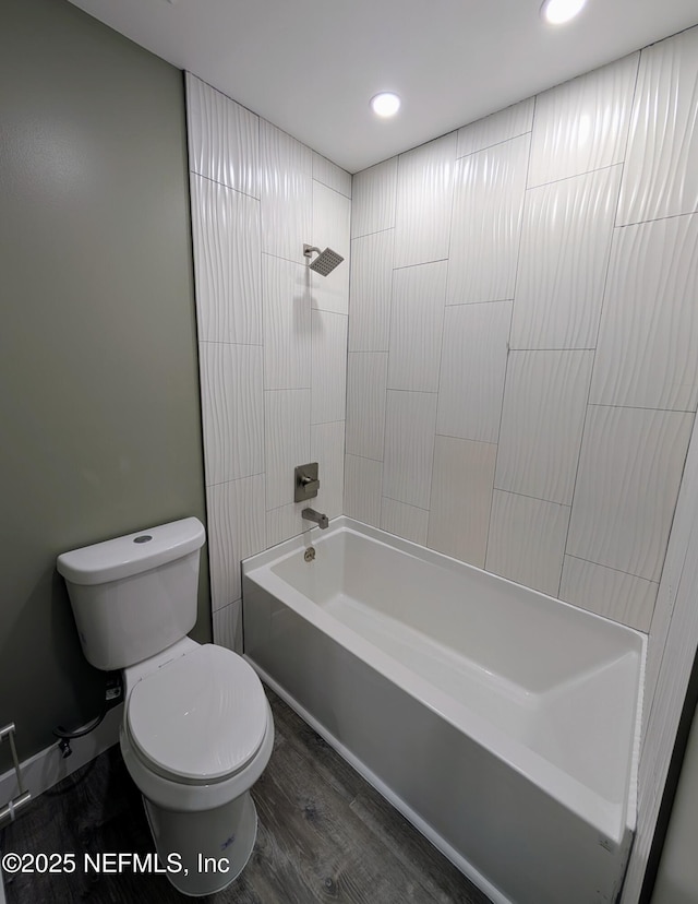 bathroom featuring tiled shower / bath, hardwood / wood-style floors, and toilet